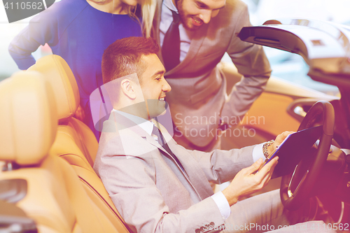 Image of happy couple with car dealer in auto show or salon