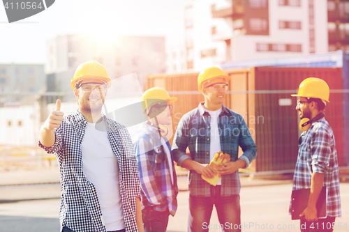 Image of group of smiling builders in hardhats outdoors