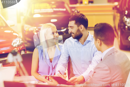 Image of happy couple with car dealer in auto show or salon