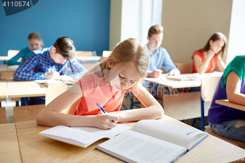 Image of student girl with book writing school test