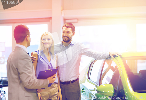 Image of happy couple with car dealer in auto show or salon