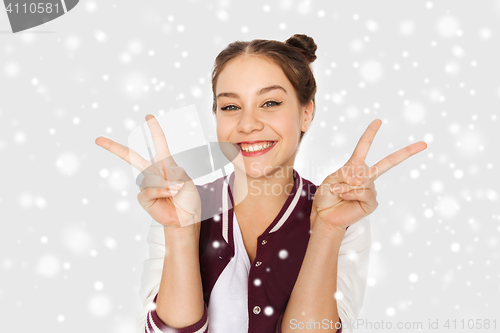 Image of happy teenage girl showing peace sign over snow