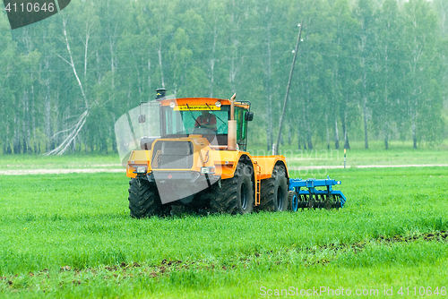 Image of Tractor operator plows the site in rain