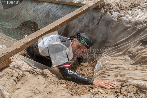 Image of Man creeps on an entrenchment with sand and water