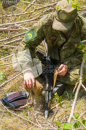 Image of Soldier cools submachine gun barrel by water