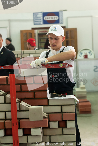 Image of Young bricklayer performs a task of competition