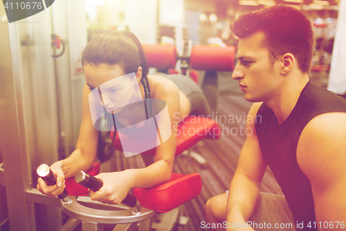 Image of young woman with trainer exercising on gym machine