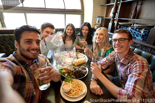 Image of happy friends taking selfie at bar or pub