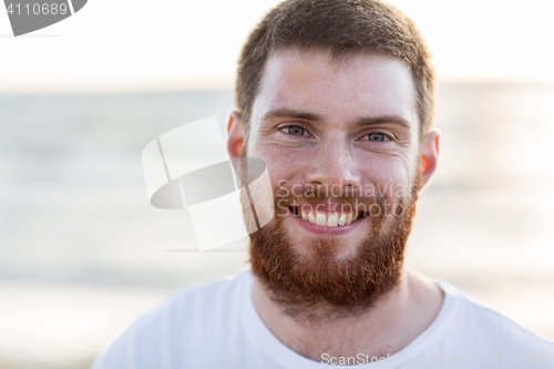 Image of face of happy smiling young man on beach