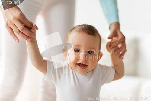 Image of happy baby learning to walk with mother help