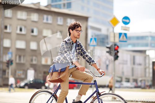 Image of young hipster man with bag riding fixed gear bike