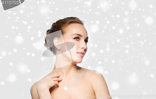 Image of beautiful young woman touching her neck over snow