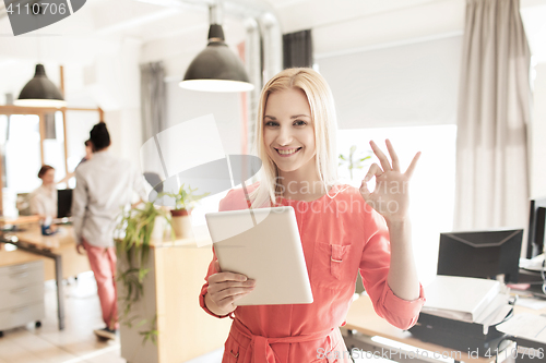 Image of woman with tablet pc showing ok sign at office
