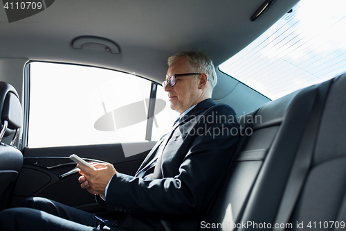 Image of senior businessman texting on smartphone in car