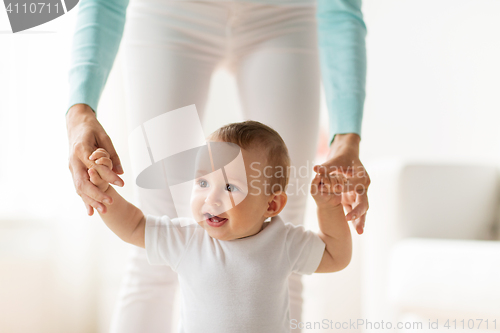 Image of happy baby learning to walk with mother help