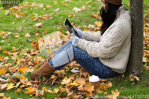 Image of woman with tablet pc and coffee in autumn park