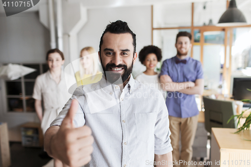 Image of happy creative team showing thumbs up in office