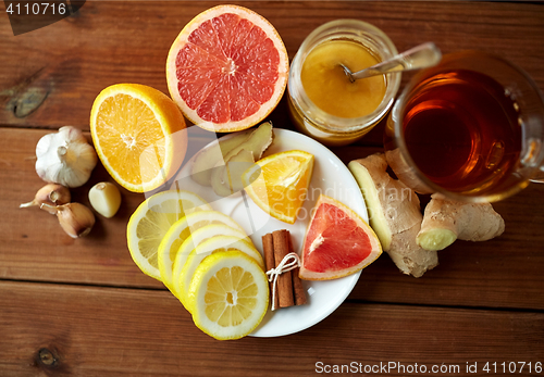 Image of ginger tea with honey, citrus and garlic on wood