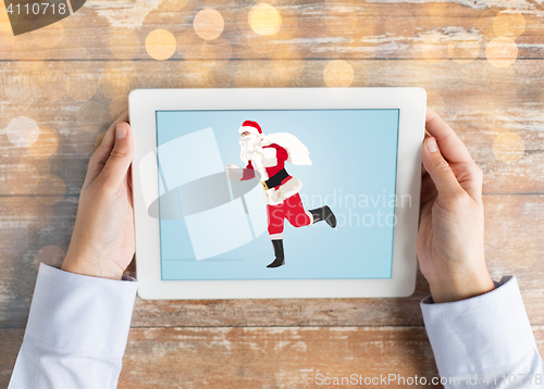 Image of close up of hands with santa claus on tablet pc