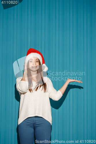 Image of Surprised christmas girl wearing a santa hat