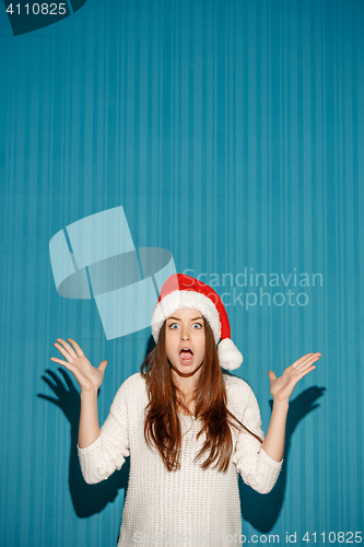 Image of Surprised christmas girl wearing a santa hat