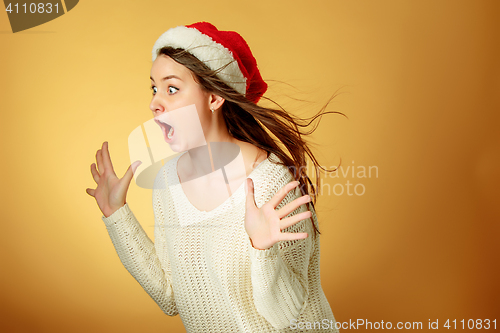 Image of Surprised christmas girl wearing a santa hat