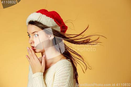 Image of Surprised christmas girl wearing a santa hat