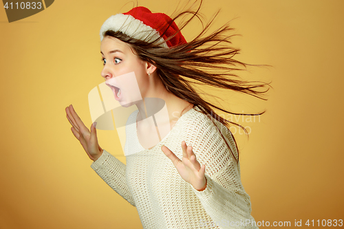 Image of Surprised christmas girl wearing a santa hat