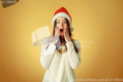 Image of Surprised christmas girl wearing a santa hat