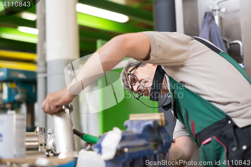 Image of Industrial worker welding in metal factory.