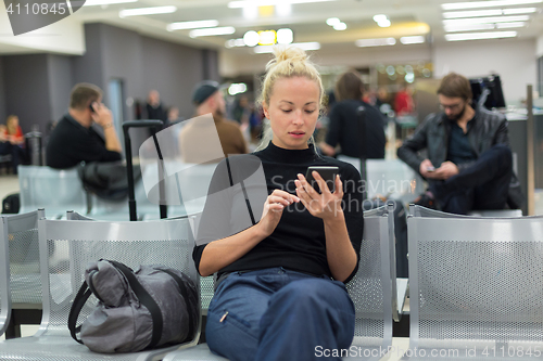 Image of Lady using smart phone while waiting at airpot departure gates.