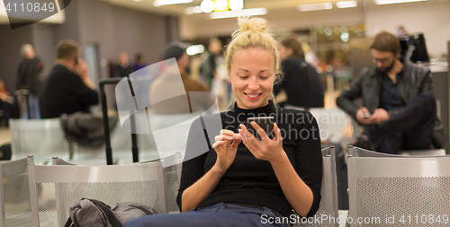 Image of Lady using smart phone while waiting at airpot departure gates.