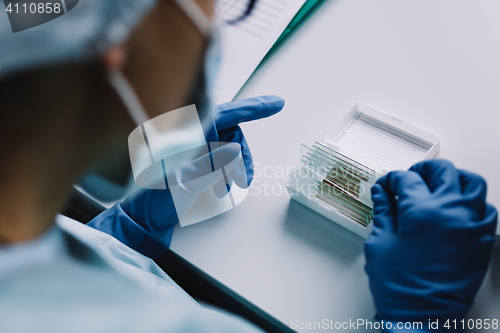 Image of Crop hands putting microscope glasses in box