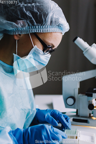 Image of Female scientist arranging microscope glasses in box