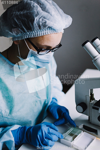 Image of Female scientist arranging microscope glasses in box