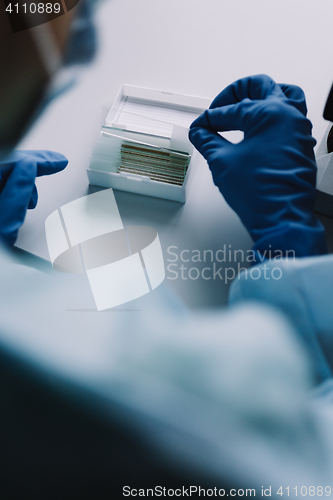 Image of Crop hands putting microscope glasses in box