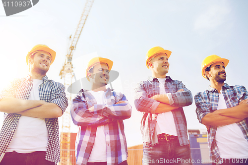 Image of group of smiling builders in hardhats outdoors