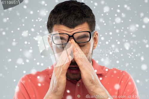 Image of tired man with eyeglasses touching his nose bridge