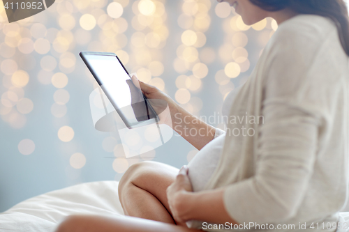 Image of close up of pregnant woman with tablet pc in bed