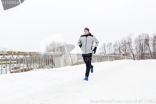 Image of man running along snow covered winter bridge road