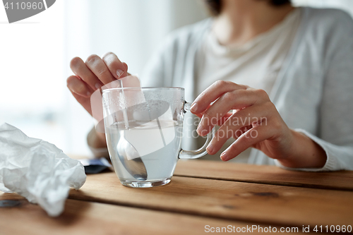 Image of woman stirring medication in cup with spoon