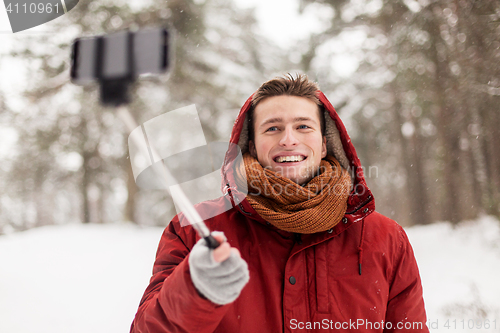 Image of happy man taking selfie by smartphone in winter