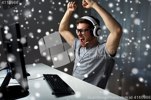 Image of man in headset playing computer video game at home