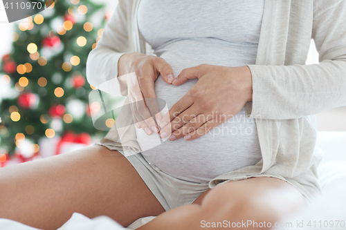 Image of close up of pregnant woman making heart gesture