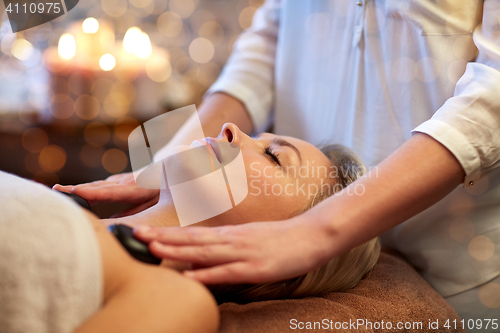 Image of close up of woman having hot stone massage in spa