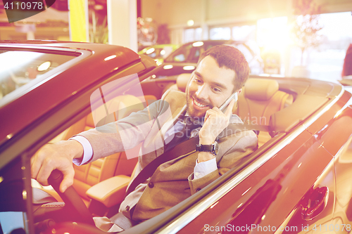Image of happy man sitting in car at auto show or salon