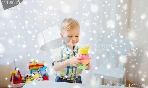 Image of happy little baby boy with ball clay at home