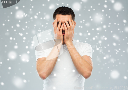 Image of man covering his face with hands over snow