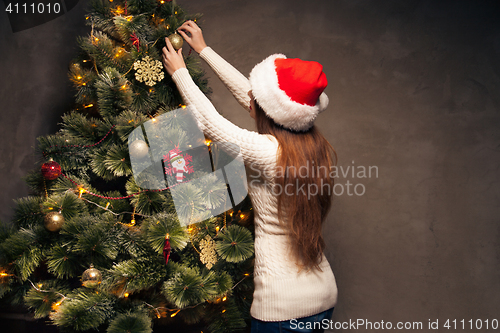 Image of Happy woman decorating a christmas tree