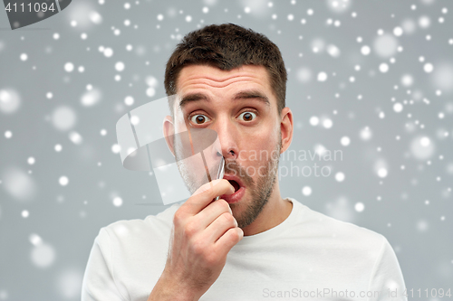 Image of man with tweezers tweezing hair from nose